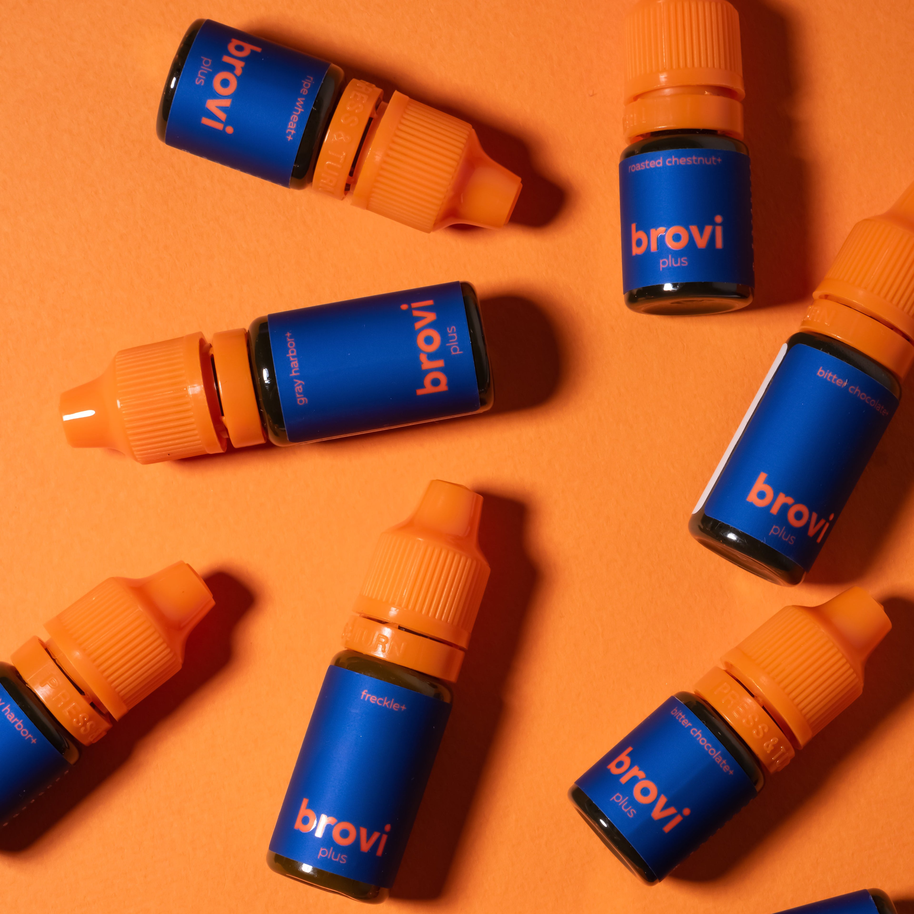 Multiple brovi bottles with blue labels and orange caps arranged on an orange background